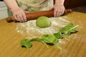 Grandmother hands kneading dough for noodles in the kitchen. photo