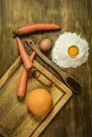 naranja masa bollo para tallarines con ingredientes en el mesa. foto