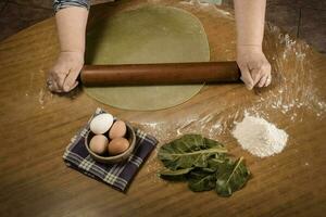 Grandma's hands kneading, dough for green noodles. photo