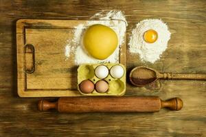 Egg dough for noodles, with ingredients on the table. photo