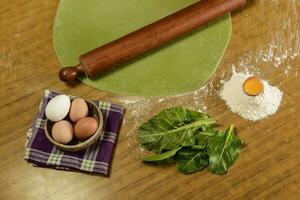 Grandma's hands kneading, dough for green noodles. photo