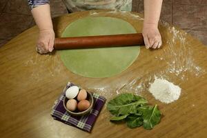 Grandma's hands kneading, dough for green noodles. photo