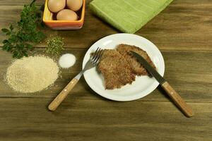 Veal milanese presented on the table with ingredients photo