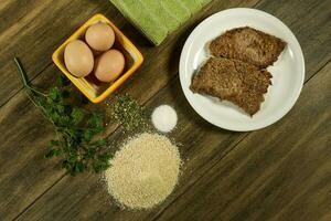Veal milanese presented on the table with ingredients photo