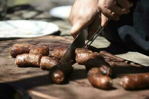 Hands cutting barbecue, grilled sausages and cow meat , traditional argentine cuisine photo