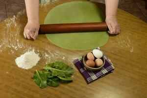 Grandma's hands kneading, dough for green noodles. photo