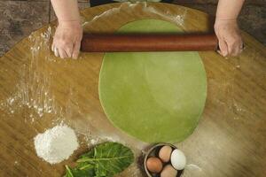 Grandma's hands kneading, dough for green noodles. photo