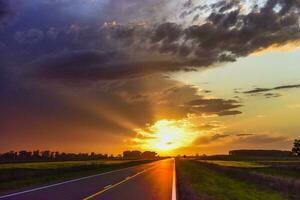 Landscape with road and stormy sky at sunset photo