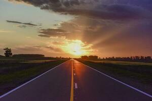 Landscape with road and stormy sky at sunset photo