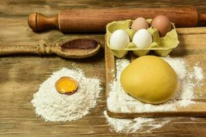 Egg dough for noodles, with ingredients on the table. photo
