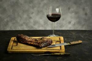 asado carne de vaca costillas con un vaso de rojo vino presentado en el mesa, tradicional argentino cocina, asado parilla, Patagonia, argentina. foto