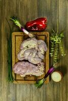 Cow bowels presented on a wooden board with ingredients, ready to grill photo