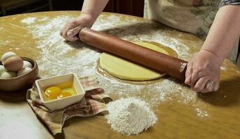 Egg dough for noodles, with ingredients on the table. photo