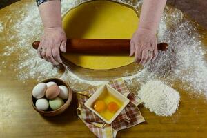 Egg dough for noodles, with ingredients on the table. photo