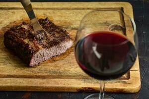 Roasted beef ribs with a glass of red wine presented on the table, traditional Argentine cuisine, Asado barbecue, Patagonia, Argentina. photo