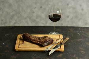 asado carne de vaca costillas con un vaso de rojo vino presentado en el mesa, tradicional argentino cocina, asado parilla, Patagonia, argentina. foto