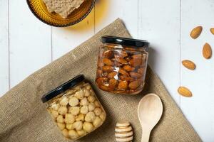 Glass jars with honey and nuts. Almonds and hazelnuts in honey photo