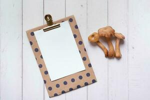 Empty paper with mushrooms on wooden background top view photo