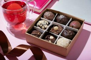 Gift box with craft chocolate candies on pink work desktop background photo