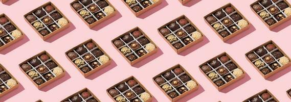 Banner with pattern made from box with chocolate craft candies with nuts inside on pink background. photo