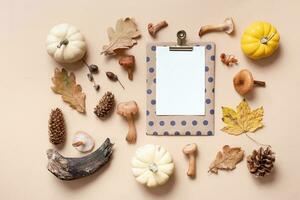 Empty paper with mushrooms and autumn leaves on beige background top view, flat lay photo