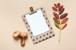 Empty paper with mushrooms and autumn leaves on beige background top view, flat lay photo