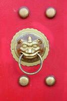 Gollden head of lion in Asian style on red wooden texture. Head of Asian lion on red door. photo
