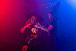 Two halloween witches making magic in halloween night. Magic, holidays and mystic concept. photo