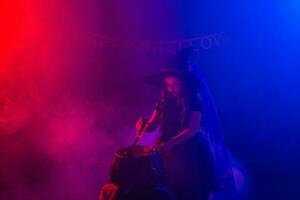 Little witch child cooking potion in the cauldron on Halloween. photo