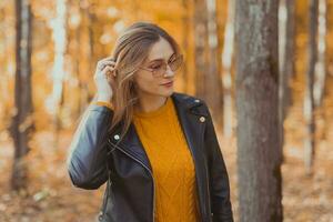 Portrait of young urban stylish young woman walking in fall park. Autumn season. photo