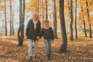 Grandmother with granddaughter in autumn park. Generation and family concept. photo