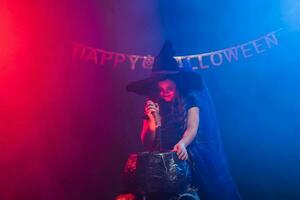 Little witch child cooking potion in the cauldron on Halloween. photo