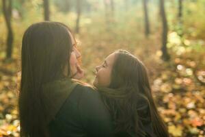 Mother and daughter spend time together in autumn yellow park. Season and single parent concept. photo