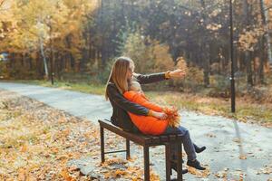 Single parent mother and child boy in the autumn in park sit on bench. Fall season and family concept. photo