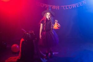 Little girl holds pumpkin jack on Halloween holiday. Kid girl wear witch costume. Fantasy, fairy tale and masquerade concept. photo