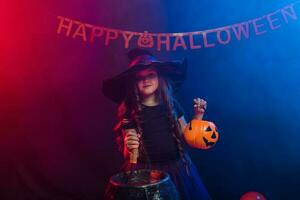 Funny child girl in witch costume for Halloween with pumpkin Jack. photo