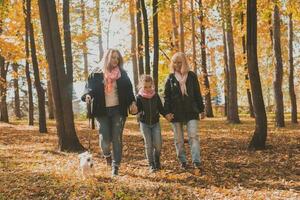 Grandmother and mother with granddaughter walks together in autumn park and having fun. Generation, leisure and family concept. photo