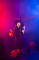 Funny child girl in witch costume for Halloween with pumpkin Jack. photo