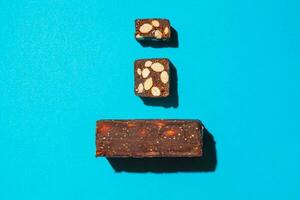 Raw pressed date with nuts and fruit bars isolated on blue background top view. Healthy gluten free snack for energy and diet photo