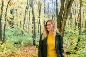 linda sonriente mujer participación otoño hojas en otoño parque. estacional, estilo de vida y ocio concepto. foto