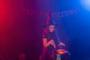 Little witch child cooking potion in the cauldron on Halloween. photo