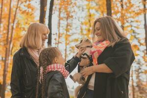 Mother and grandmother and daughter holds jack russell terrier and plays with it in autumn outside. Pet and family concept photo