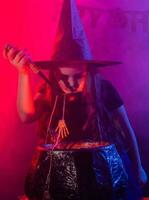 Child girl witch preparing a potion in the cauldron at halloween holidays. photo
