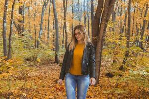 Girl holds fallen leaves and walks in autumn park. Seasonal concept. photo