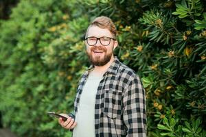 Laughing attractive man wearing hat over green tree background - emotion and vacation travel holidays concept photo