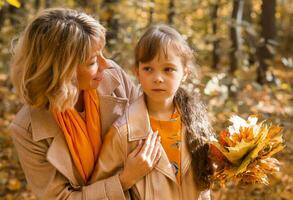 madre calma su infeliz triste hija en otoño naturaleza. niños depresión concepto foto
