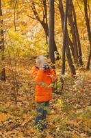 Boy with retro camera taking pictures outdoor in autumn nature. Leisure and photographers concept photo