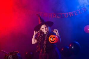 Funny child girl in witch costume for Halloween with pumpkin Jack. photo