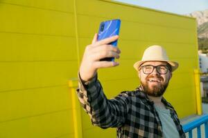 Man telling something at the camera while traveling at new city, yellow supermarket background. Blogger and vlog concept photo