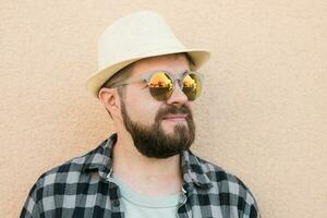 Bearded man portrait in summer clothes and hat stand over beige wall on street city urban and travel concept photo